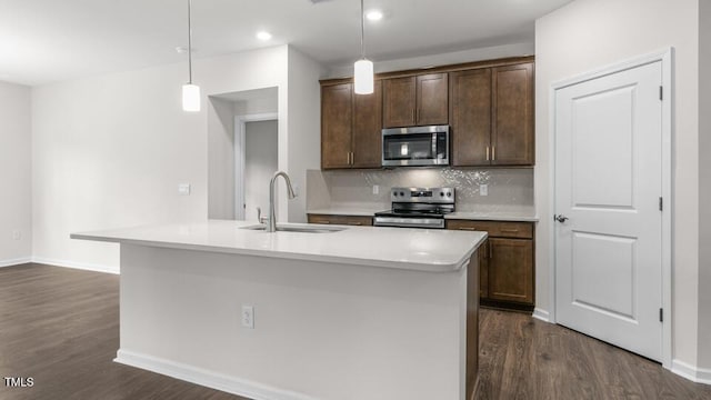 kitchen with decorative light fixtures, sink, stainless steel appliances, and an island with sink