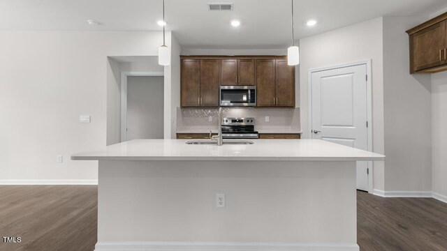 kitchen featuring pendant lighting, dark brown cabinetry, a center island with sink, and stainless steel appliances