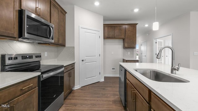 kitchen featuring pendant lighting, backsplash, dark wood-type flooring, sink, and appliances with stainless steel finishes