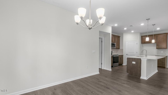 kitchen with appliances with stainless steel finishes, a kitchen island with sink, sink, dark hardwood / wood-style floors, and hanging light fixtures