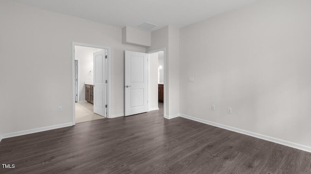 unfurnished bedroom with ensuite bath and dark hardwood / wood-style flooring