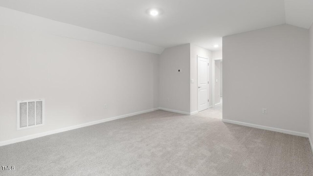 additional living space featuring light colored carpet and vaulted ceiling