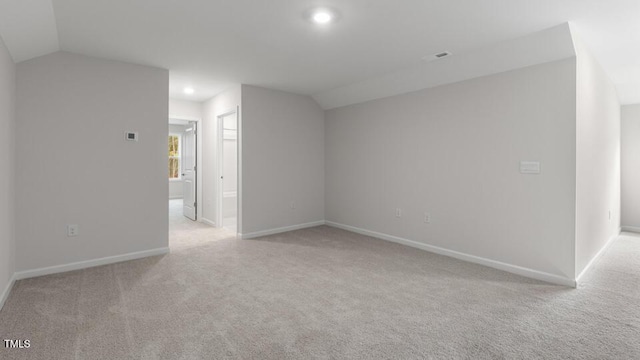 carpeted empty room with vaulted ceiling