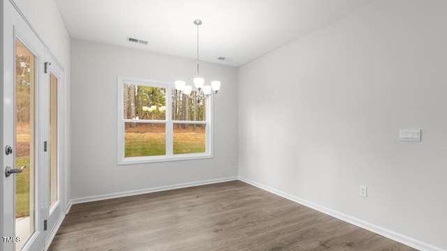 unfurnished dining area with hardwood / wood-style floors and an inviting chandelier