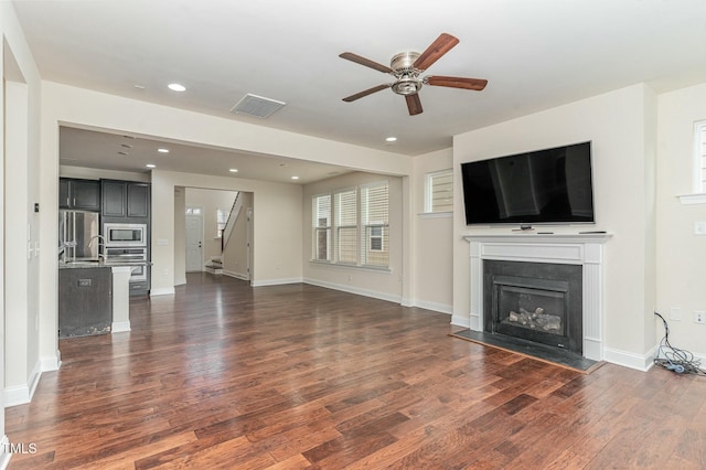 unfurnished living room featuring dark wood-type flooring and ceiling fan