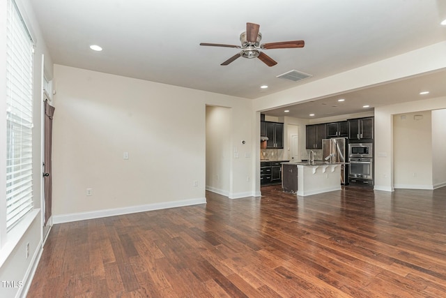 unfurnished living room featuring ceiling fan, dark hardwood / wood-style floors, and sink