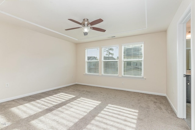 empty room featuring ceiling fan, a tray ceiling, and light carpet