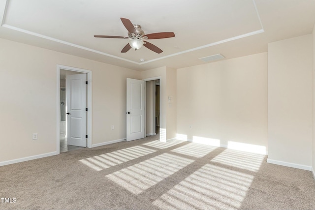 carpeted empty room featuring ceiling fan and a raised ceiling