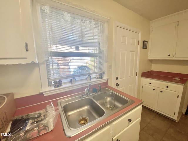 kitchen with white cabinetry, sink, and dark tile patterned floors