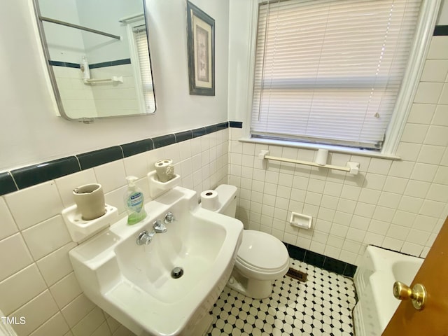 bathroom featuring sink, tile patterned flooring, toilet, tile walls, and a tub