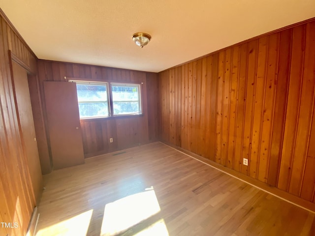 spare room featuring light wood-type flooring and wooden walls