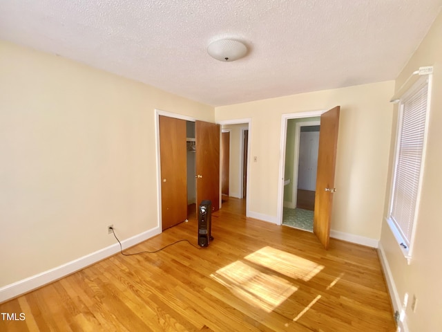 unfurnished bedroom featuring hardwood / wood-style floors, a textured ceiling, and a closet