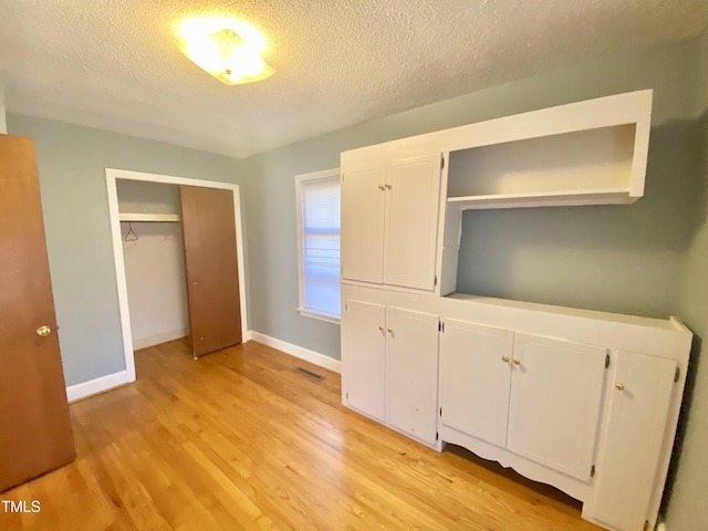 unfurnished bedroom with a closet, a textured ceiling, and light hardwood / wood-style flooring