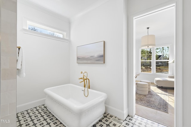 bathroom featuring a washtub, a wealth of natural light, and ornamental molding