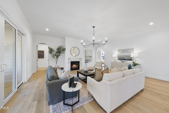 living room with an inviting chandelier, light hardwood / wood-style flooring, and crown molding