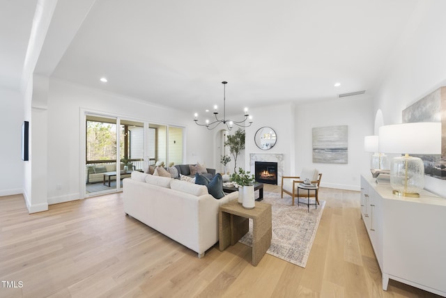 living room featuring light hardwood / wood-style floors, a notable chandelier, and a premium fireplace