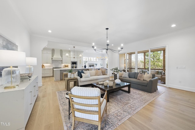 living room with an inviting chandelier, light hardwood / wood-style flooring, and crown molding