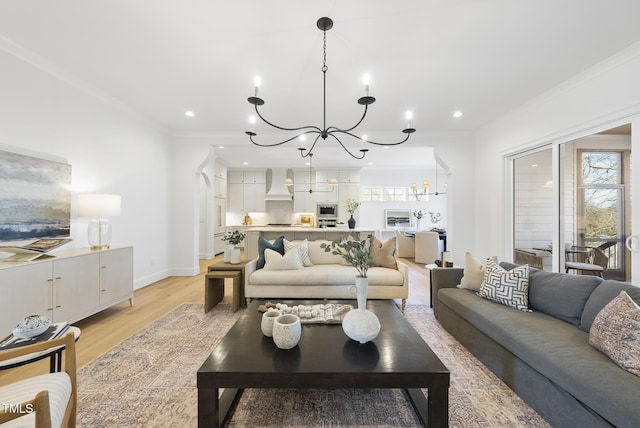 living room featuring light hardwood / wood-style floors, ornamental molding, and a notable chandelier