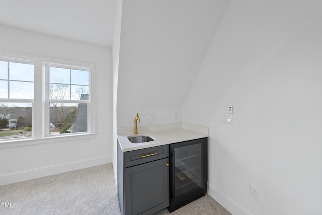 bar featuring light carpet, gray cabinetry, vaulted ceiling, beverage cooler, and sink