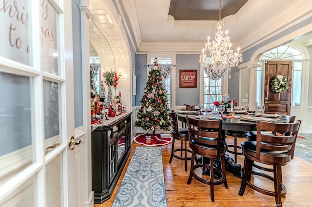 dining room featuring light hardwood / wood-style floors, crown molding, a tray ceiling, and an inviting chandelier