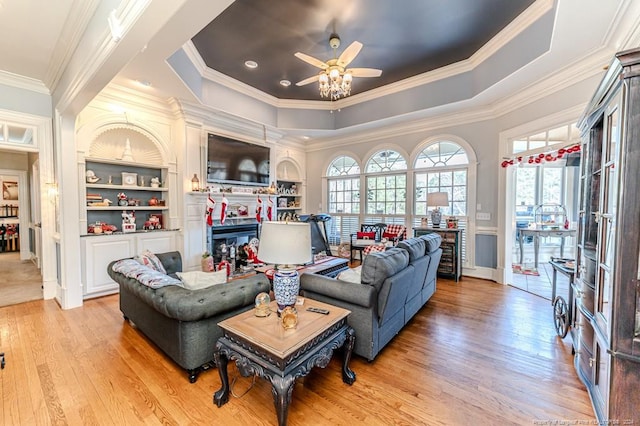 living room with a raised ceiling, light hardwood / wood-style flooring, ceiling fan, and ornamental molding