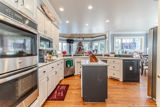 kitchen with a healthy amount of sunlight, a kitchen island, ornamental molding, and stainless steel appliances