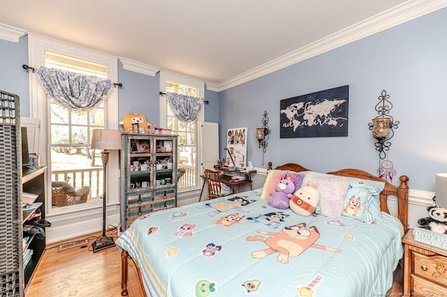 bedroom with crown molding, wood finished floors, and visible vents