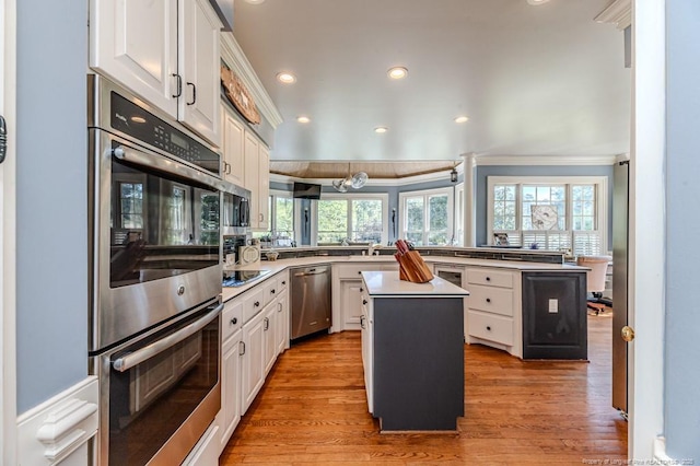kitchen featuring stainless steel appliances, a wealth of natural light, a peninsula, and ornamental molding