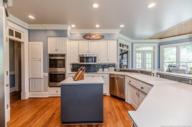 kitchen featuring crown molding, appliances with stainless steel finishes, a sink, and white cabinetry