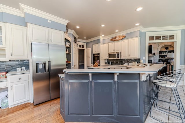 kitchen with stainless steel appliances, white cabinetry, a breakfast bar area, and crown molding