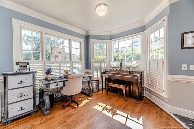 home office featuring light wood-style floors, ornamental molding, and visible vents
