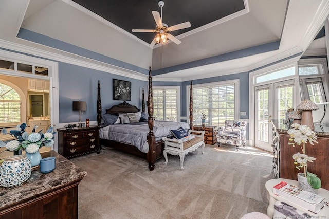 carpeted bedroom with a raised ceiling, access to outside, crown molding, and multiple windows