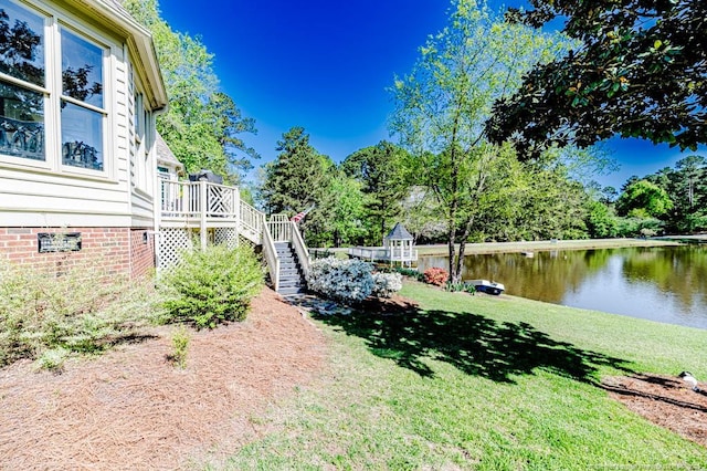 view of yard featuring a deck with water view and stairs