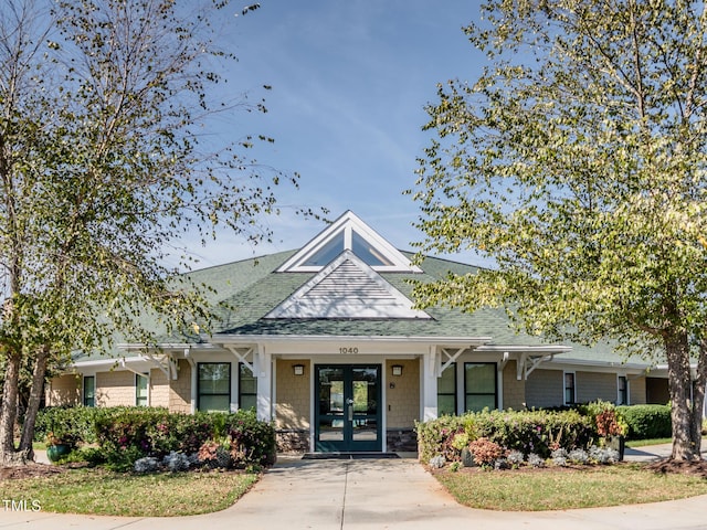 view of front of property featuring french doors and roof with shingles