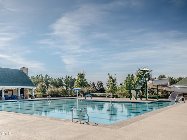 community pool featuring a water slide and a patio area