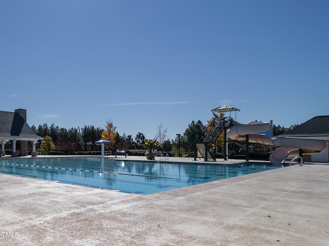 pool with a patio area and a water slide