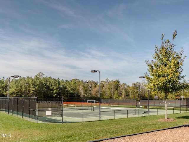 view of tennis court featuring fence and a yard