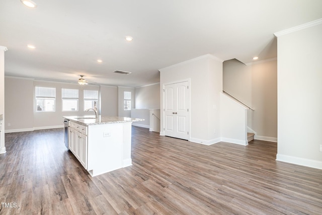 kitchen with sink, wood-type flooring, white cabinets, and an island with sink