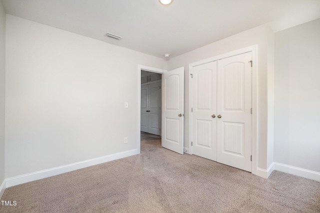 unfurnished bedroom with light colored carpet and a closet