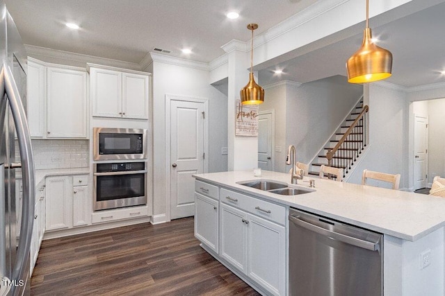 kitchen featuring white cabinets, sink, appliances with stainless steel finishes, decorative light fixtures, and dark hardwood / wood-style flooring