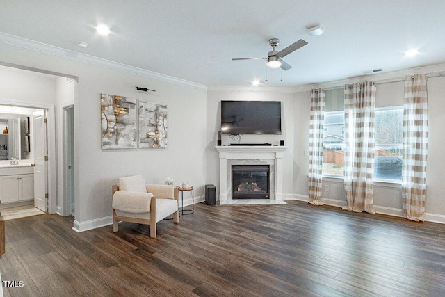 living area featuring ceiling fan, sink, dark wood-type flooring, a premium fireplace, and ornamental molding