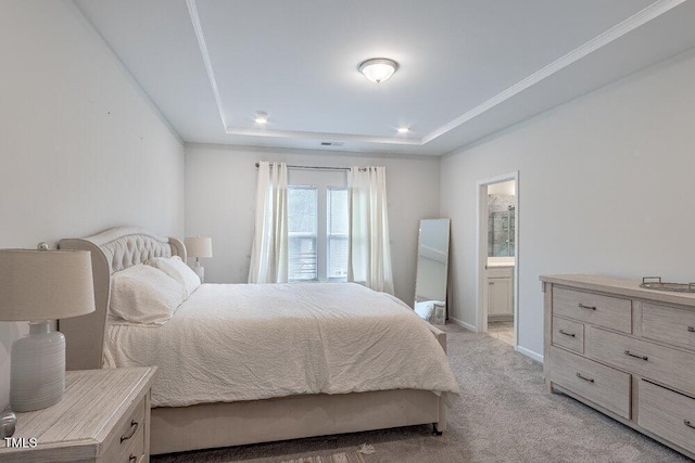 bedroom with a raised ceiling, ensuite bath, and light colored carpet