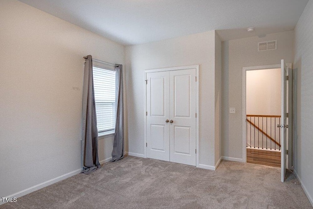 unfurnished bedroom with light carpet and a closet