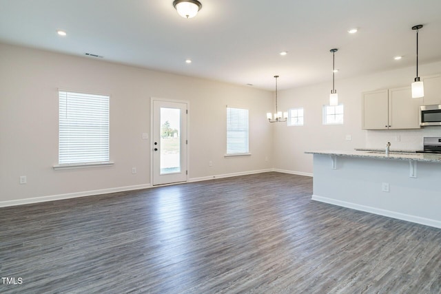 unfurnished living room with a chandelier and dark hardwood / wood-style floors