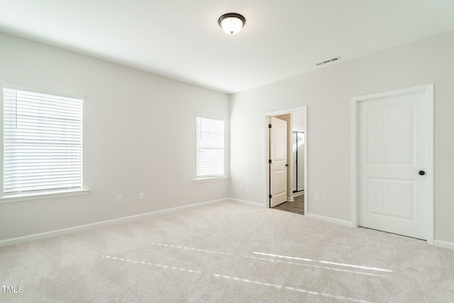 unfurnished bedroom featuring light colored carpet and connected bathroom