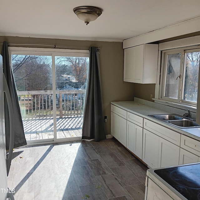 kitchen featuring electric stove, sink, white cabinets, and a healthy amount of sunlight