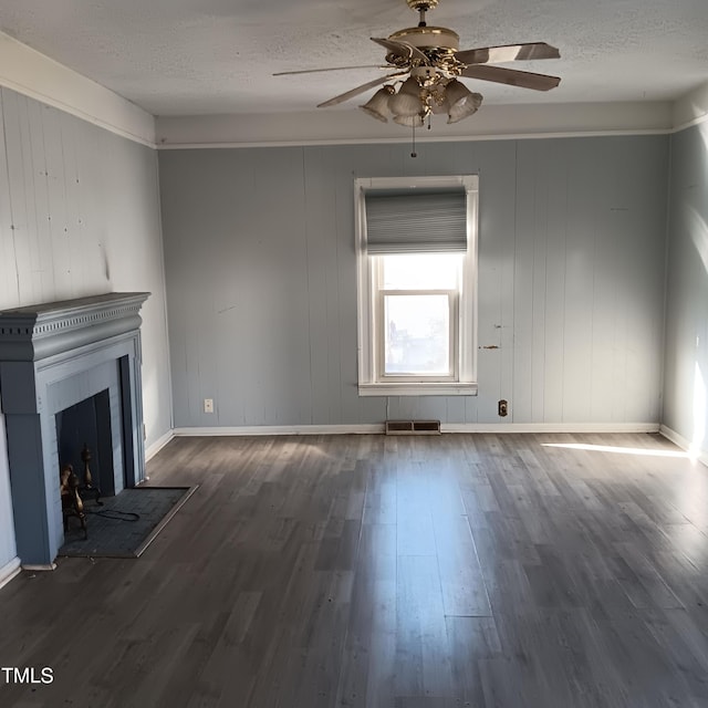 unfurnished living room with a textured ceiling, dark hardwood / wood-style flooring, ceiling fan, and wooden walls