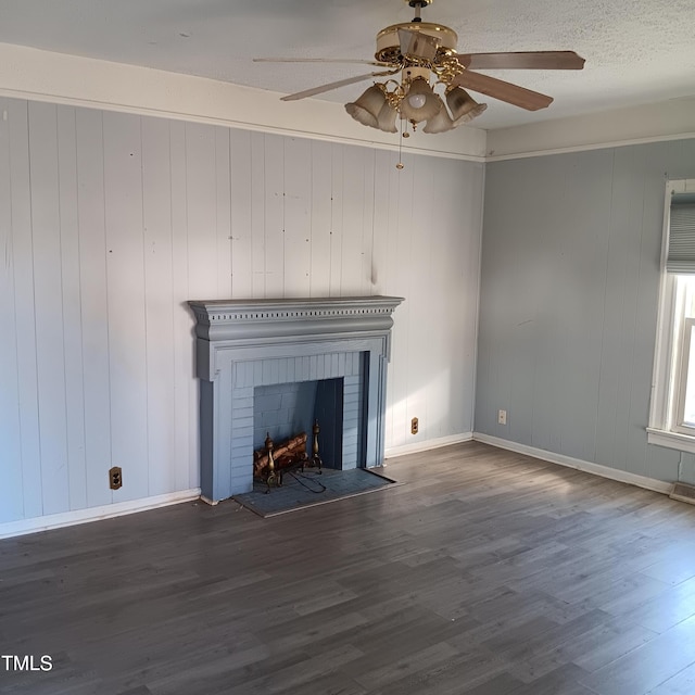 unfurnished living room with ceiling fan, wood-type flooring, wood walls, and a brick fireplace