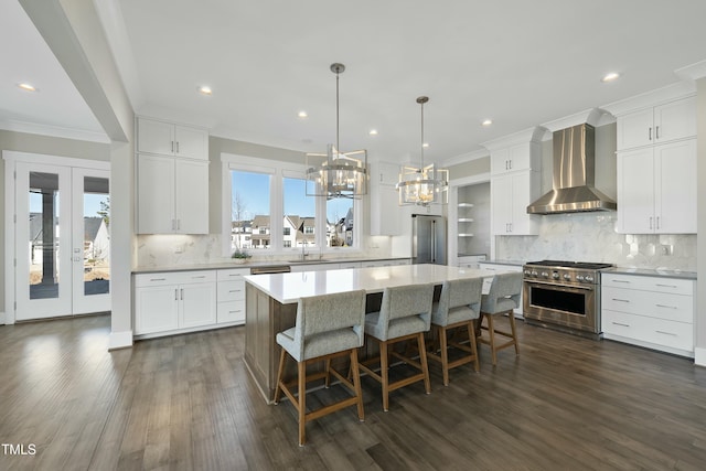 kitchen featuring sink, a center island, wall chimney exhaust hood, premium appliances, and white cabinets