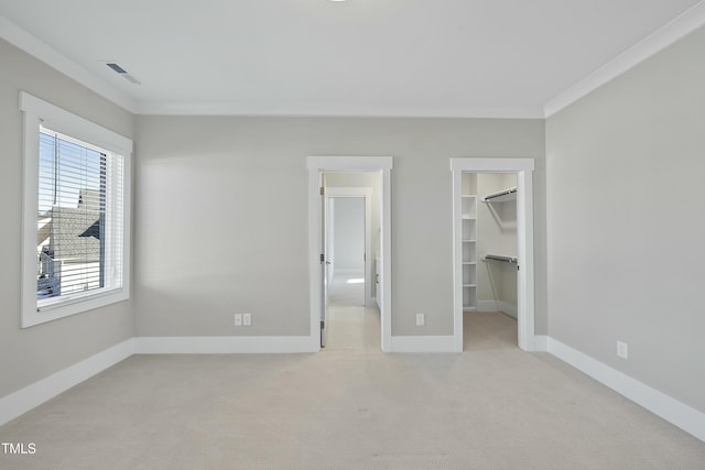 unfurnished bedroom with light colored carpet, a walk in closet, crown molding, and a closet